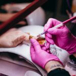 Close-up of a nail technician applying nail art in a beauty salon setting, highlighting precision and artistry.