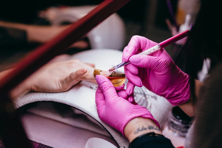 Close-up of a nail technician applying nail art in a beauty salon setting, highlighting precision and artistry.